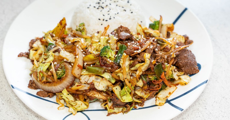 A plate of beef stir fry and a side of rice