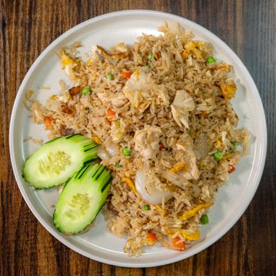 Crab fried rice with vegetables and sliced cucumber on a white plate.