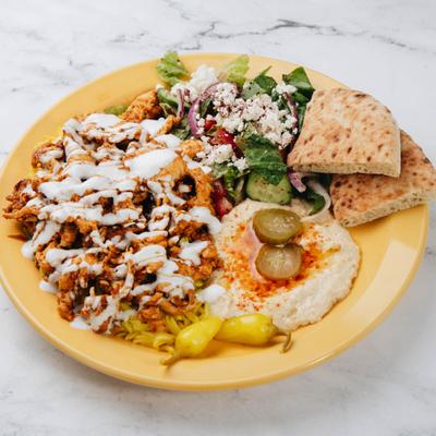 Chicken Shawarma Plate with sides of hummus, pita, fresh and pickled vegetables.
