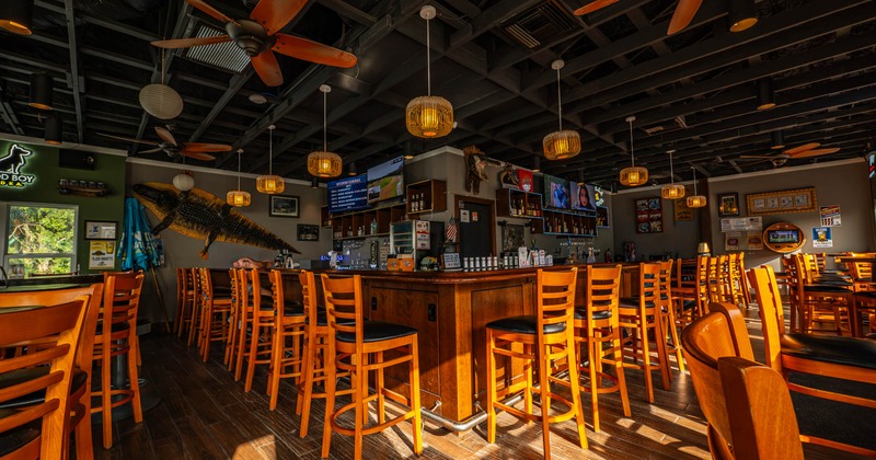 Interior of a bar with a wooden counter and high stools, featuring pendant lights