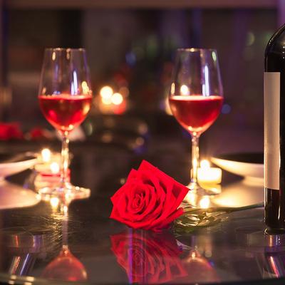 Glasses of rose wine, a red rose, lit candles.