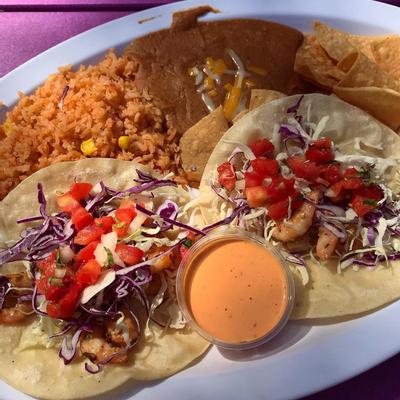 Two tortillas topped with chicken, red cabbage, onions, rice and a dip