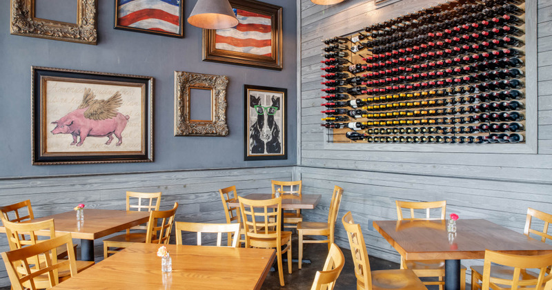 Interior, tables by the walls decorated with pictures and wine shelves