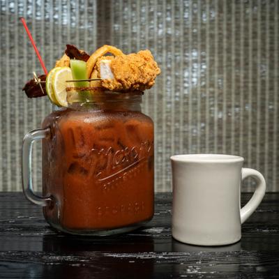 Bloody Mary cocktail with edible garnishes next toa coffee cup.