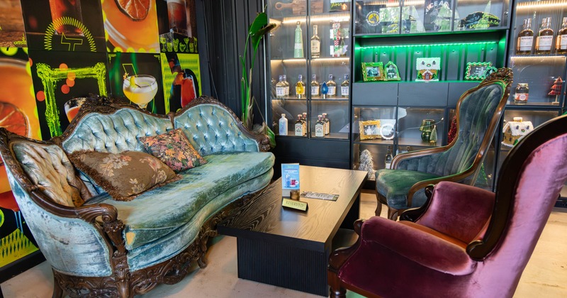 Seating area with stylish furniture next to shelves with drinks, photos, and merchandise