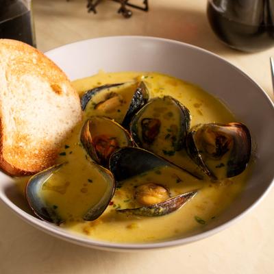 Mussels in creamy soup served with bread on the side.