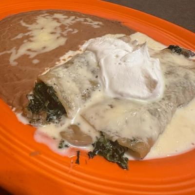 Two spinach enchiladas, refried beans, sour cream.