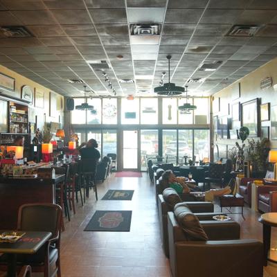 Bright cigar lounge with rows of leather armchairs and a large glass storefront.