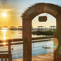 A serene sunset over water with a wooden bridge in the foreground.