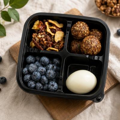 Bento box with a boiled egg, blueberries, protein balls, and granola.