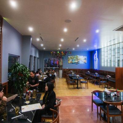 Restaurant dining area with people seated at tables and lantern decor.