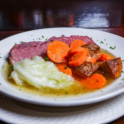 Corned beef and cabbage served with carrots, potatoes.