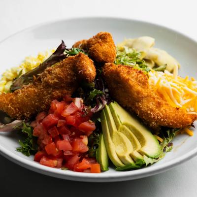 Fried chicken salad with mixed greens, avocado, cheese, and tomatoes.