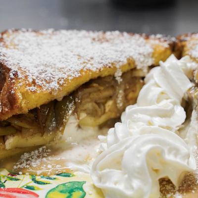 Apple-stuffed French toast topped with whipped cream and powdered sugar.