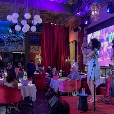 A singer on the stage and people seated at the tables enjoying.