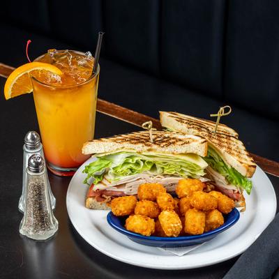 Turkey club sandwich, served with tater tots and a drink.