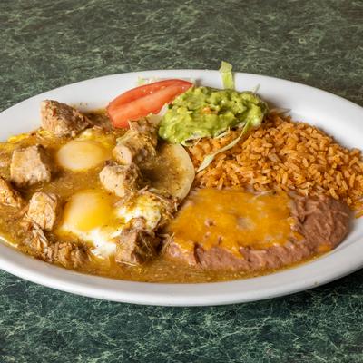 Mexican breakfast plate featuring eggs, chile verde pork, refried beans, rice, and guacamole.