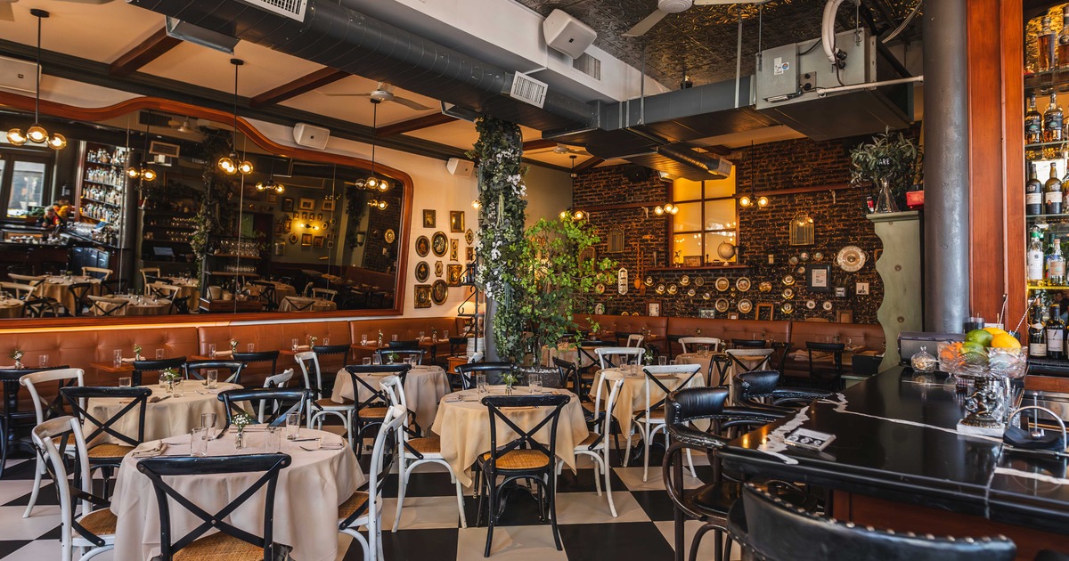 Restaurant dining room with round tables, bar seating, and decorative wall plates