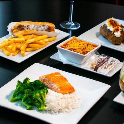 Seared salmon with rice and broccoli accompanied by chili and a sub sandwich with fries.