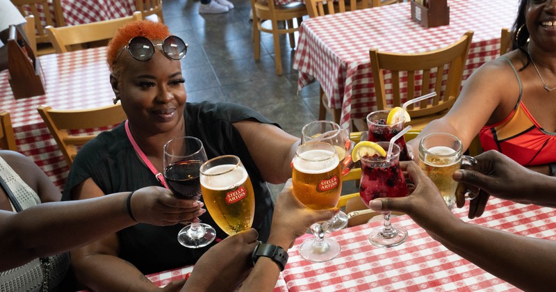 Friends toasting with beer, wine, and cocktails at a restaurant