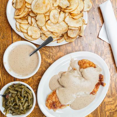 Fried Chicken topped with gravy, served with potato chips and green beans.