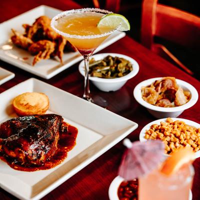 Dinner table with BBQ chicken, cocktails, and sides.