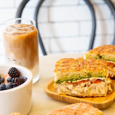Grilled chicken focaccia sandwich, fruit bowl, and iced coffee.