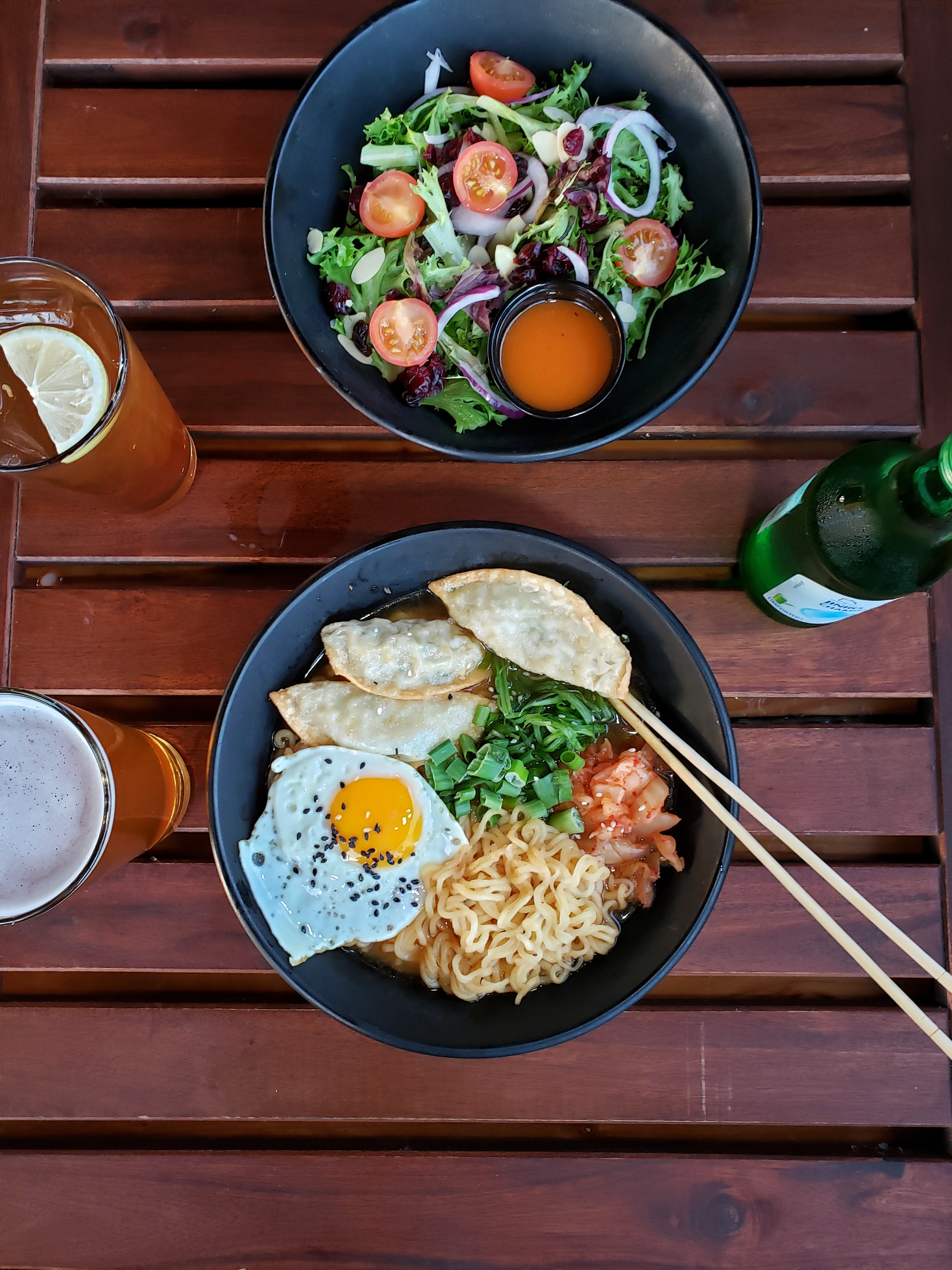 a table with noona's noodle soup, house salad and soju bottles