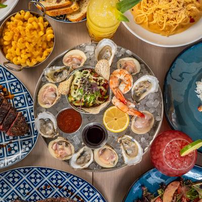 Seafood Tasting for Four platter surrounded by assorted dishes and drinks, top view.