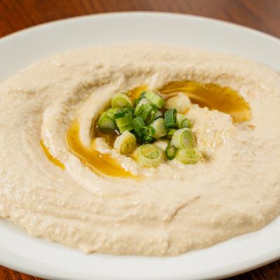 Hummus drizzled with olive oil and topped with scallions.