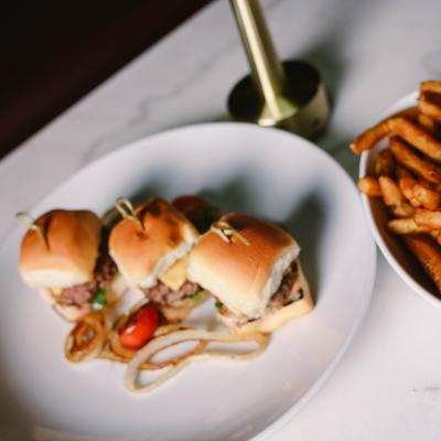 Slider cheeseburgers served with fries on the side.