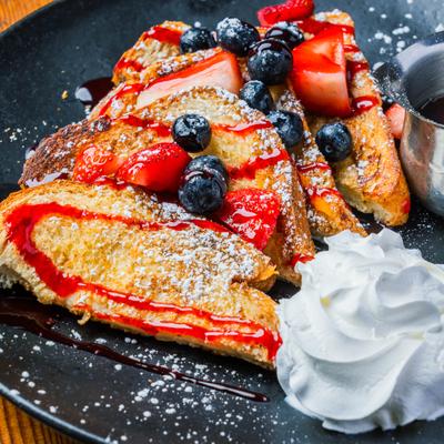 Brioche French toast topped with fresh berries, served with whipped cream and syrup.