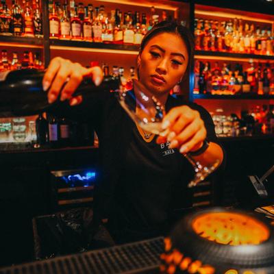 A bartender pouring drinks behind counter