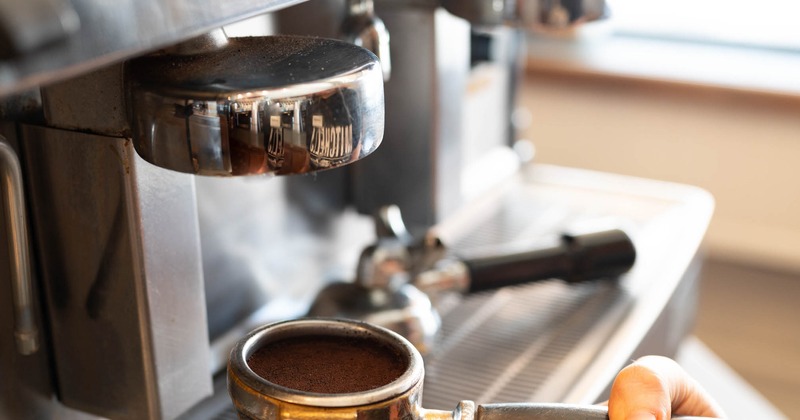 A barista holds a portafilter to prepare a shot of espresso