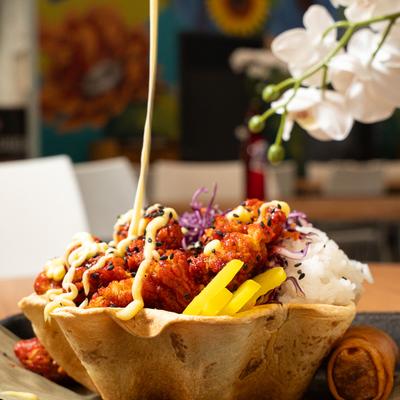 Spicy chicken buldak rice bowl being drizzled with a sauce.