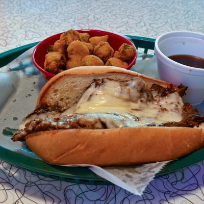 French Dip sandwich served with a side of au jus and fried okra.