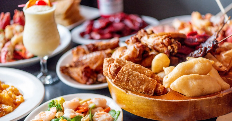 Pu Pu platter for two with various other dishes and a cocktail drink