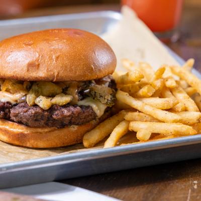 Cheeseburger with green chile sauce, fried jalapenos, onions, and fries.