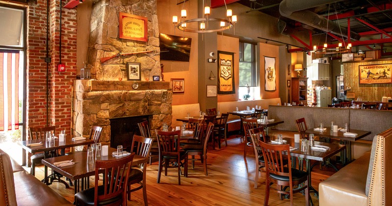 Rustic restaurant interior, dining area with wooden furnishings and a large stone fireplace