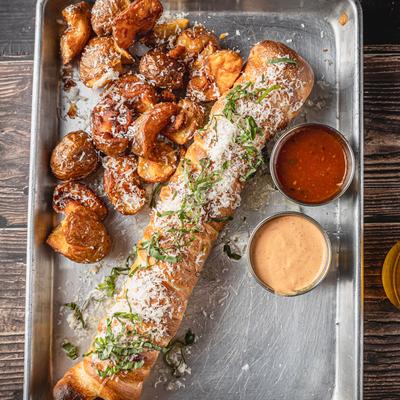 Garlic knot dog with Parmesan sweet potatoes and dipping sauces.