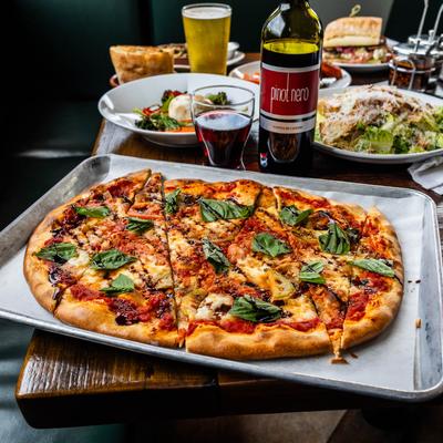 Various dishes and drinks displayed on a table with Fresh Mozz Pizza as the centerpiece.