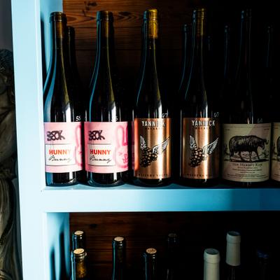 Assorted wine bottles displayed on a blue shelf.