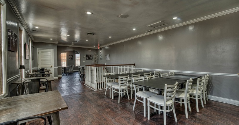 Interior view of a dining area with wooden flooring, gray walls, and tables with chairs