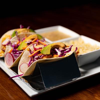 Tacos, with red cabbage, shredded carrots, avocado, and radish.
