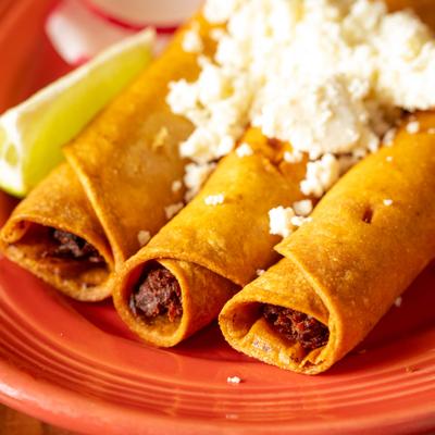 Taquitos topped with fresh cheese and lime.