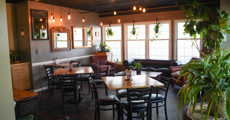 Cozy restaurant lounge with wooden tables, leather seating, and plants