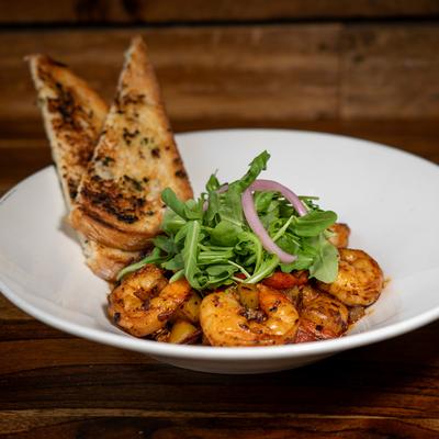 Sauteed shrimp with salsa macha, arugula, tomatoes, mezcal sauce, and garlic bread.
