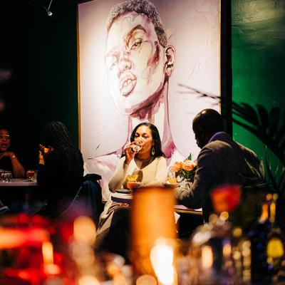 People dining in a restaurant with a mural on the wall.
