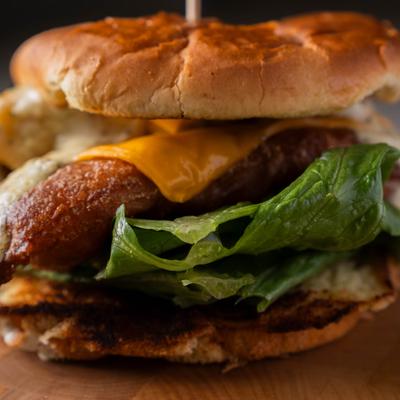 A cheeseburger with melted cheese, lettuce, sauce, a browned patty & a toasted bun.