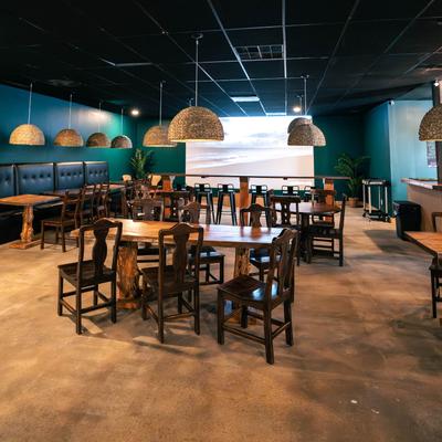 Interior featuring wooden tables, chairs, pendant lights, and a large screen.